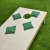 Set aus dunkelgrünen Cornhole Wurfsäcken auf einem Holzspielbrett, ideal für Spiele im Freien