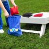 WOFEU Cornhole Säckchen Set mit roten und schwarzen Wurfsäckchen auf einer Holzbank in einer grünen Wiese, ideal für Outdoor-Spiele und Familienunterhaltung.