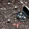 Kikkerland GG90 Boules Set S mit metallischen Kugeln und schwarzem Etui auf dunklem Rindenmulch, ideal für Freizeitaktivitäten im Freien.