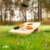 Offizielles Cornhole Set 90x60 in Rot und Schwarz mit zwei Spielbrettern, vier farbigen Wurfbeuteln und Schutzhülle, ideal für Outdoor-Partys und Familienfeiern.
