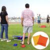 Bunte Yuragim Cornhole Säckchen auf einem Outdoor-Spielplatz mit vier Personen, die beim Spielen sichtbar sind. Das Bild zeigt eine lebendige Atmosphäre bei sonnigem Wetter.